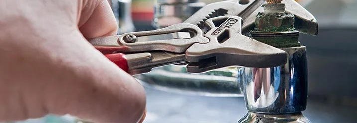 Hand verwendet Rohrzange an Wasserhahn.